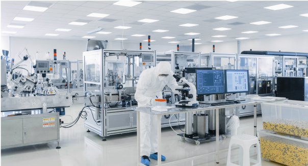 A man in a white lab coat is focused on his work at a computer, representing Pharma Access Capabilities.